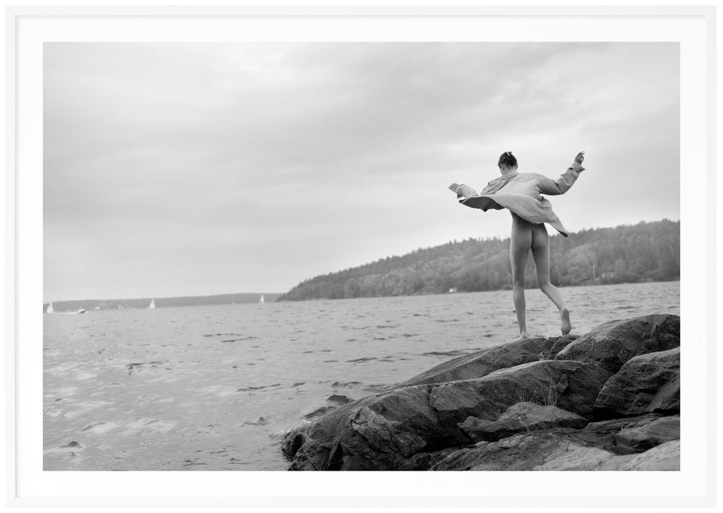 Black and white photograph of a woman on rocks in the archipelago.  White frame. 