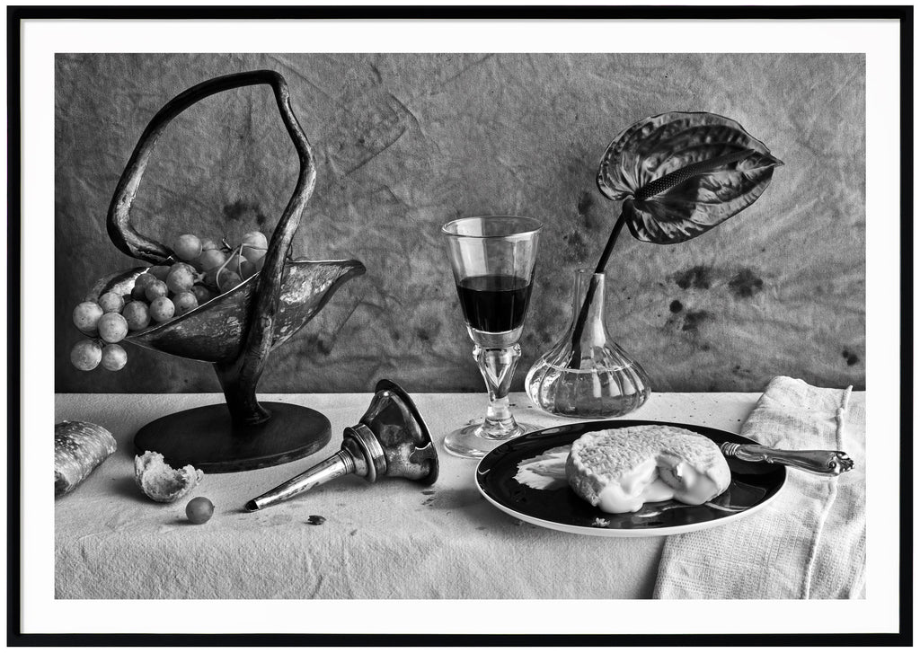  Still life in black and white of a table set with cheese and wine. Black frame. 