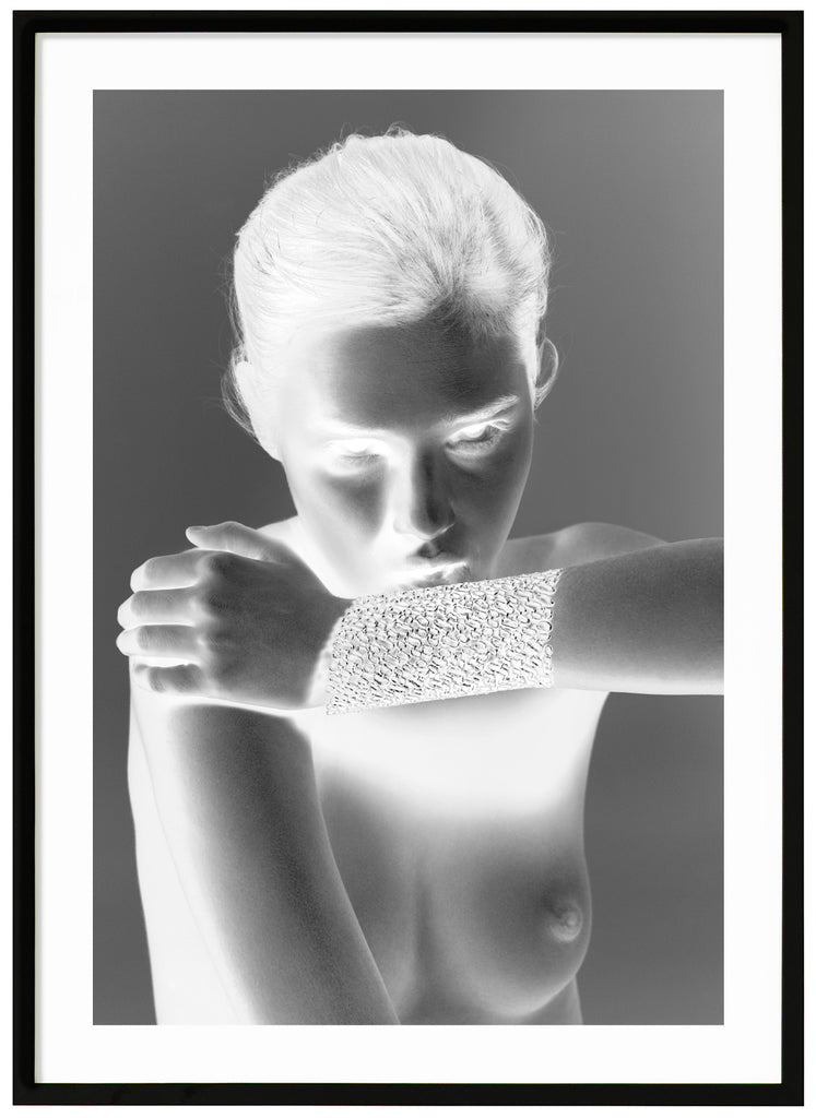  Black and white fashion photography with special effect of a naked woman wearing only an exclusive gold bracelet. Black frame. 
