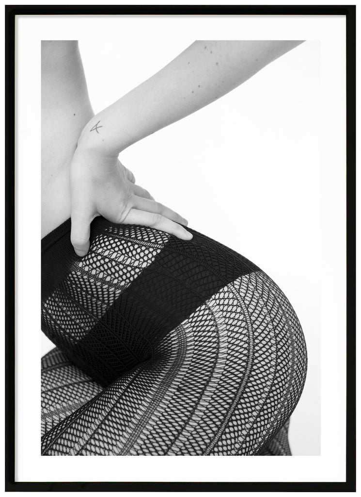 Black and white poster of sitting woman wearing black panties and fishnet tights. Portrait format. Black frame.