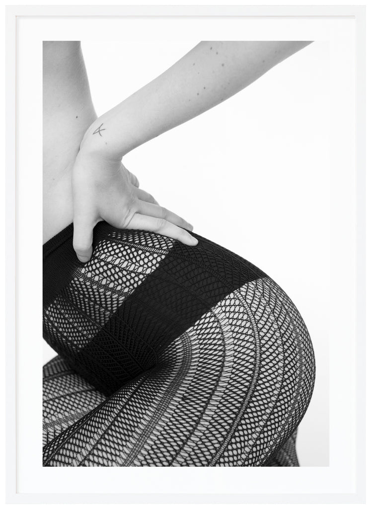 Black and white poster of sitting woman wearing black panties and fishnet tights. Portrait format. White frame.