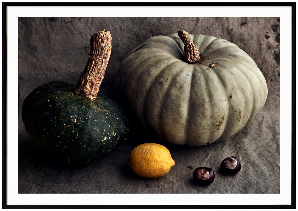 Still life in the color of a pumpkin, lemon and chestnuts. Black frame. 