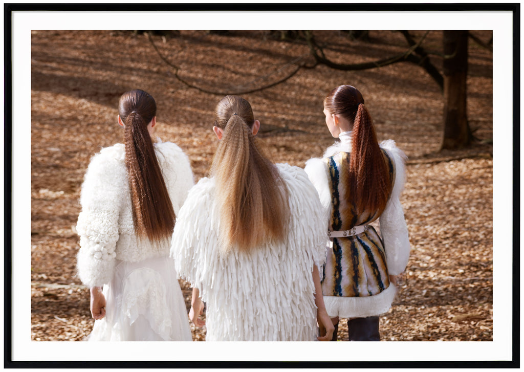 Fashion photograph of three women in long ponytails. Black frame. 