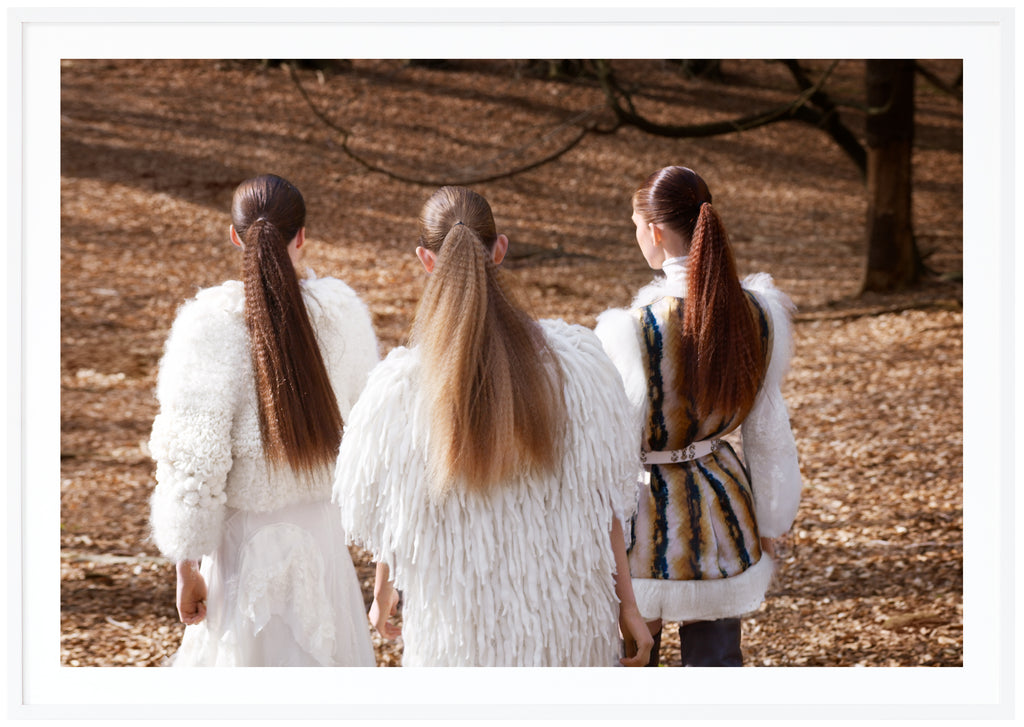 Fashion photograph of three women in long ponytails. White frame. 