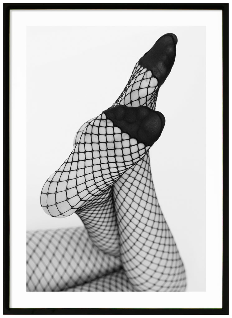 Black and white photograph of a woman's legs with her feet angled towards the camera, she is wearing net tights. Black frame. 