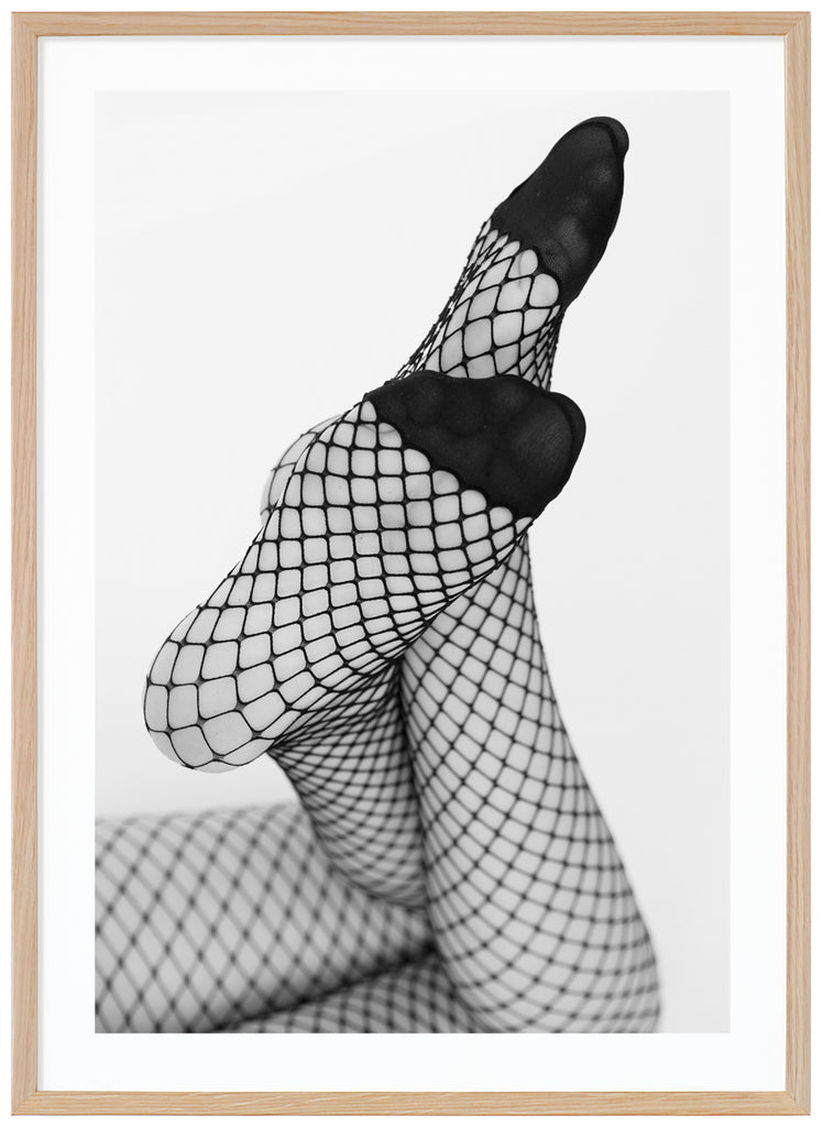 Black and white photograph of a woman's legs with her feet angled towards the camera, she is wearing net tights. Oak frame. 