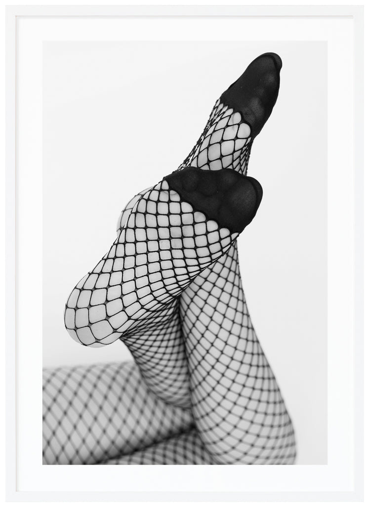 Black and white photograph of a woman's legs with her feet angled towards the camera, she is wearing net tights. White frame. 