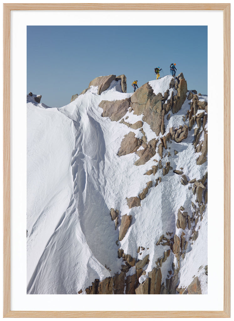 Color photograph of three mountain climbers on top of steep cliffs. Oak frame. 
