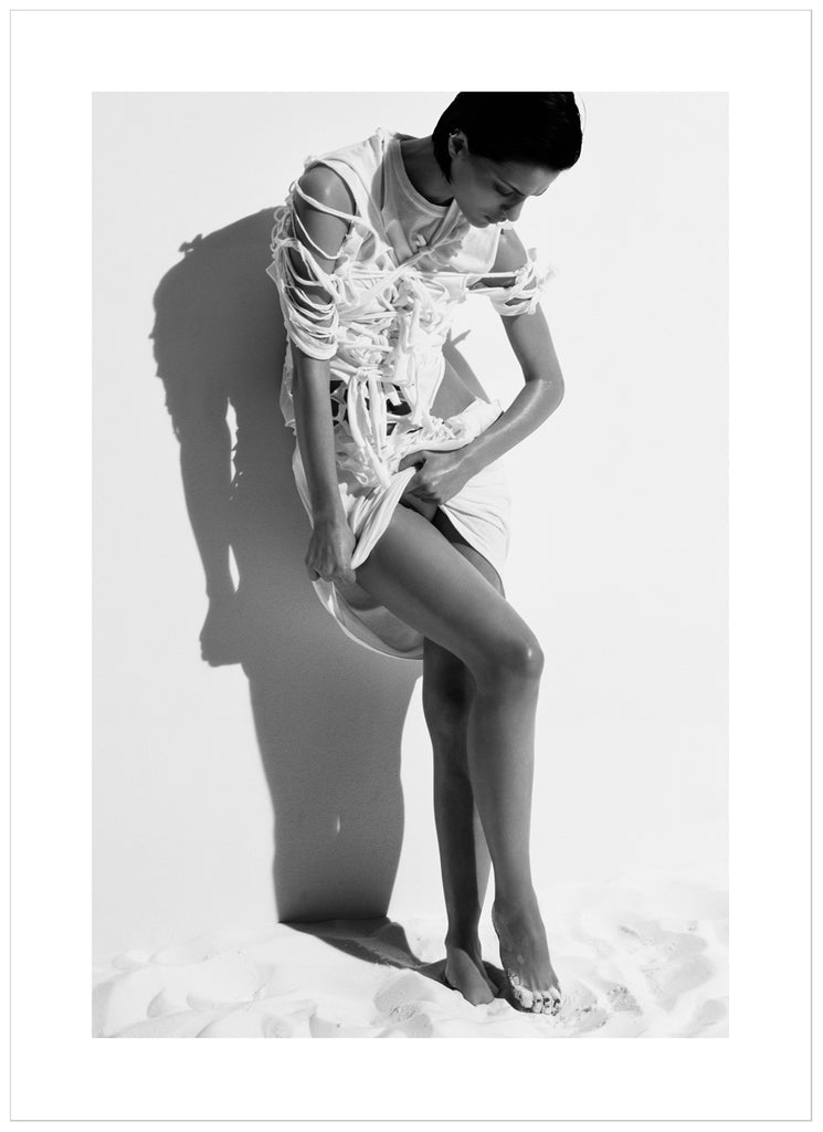 Black and white photograph a posing woman in white stringy clothes.