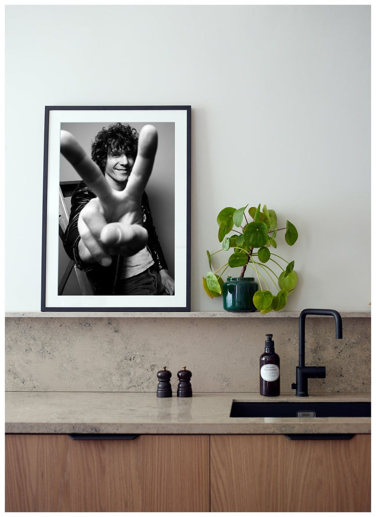 We see our Håkan holding up a peace sign with his fingers in front of the camera. Black frame in kitchen. 