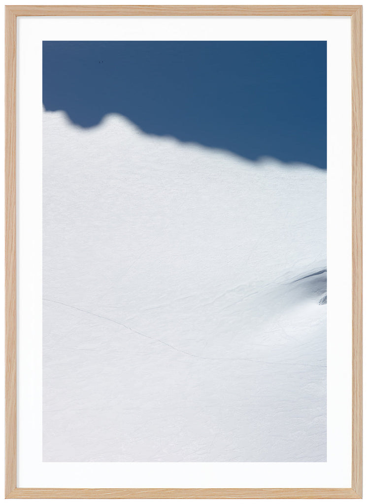 Color photography of a huge snow-covered surface with two skiers who are barely visible. Oak frame.