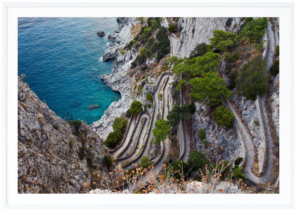 Color photography of a view of a stone promenade on the Italian island of Capri. White frame. 