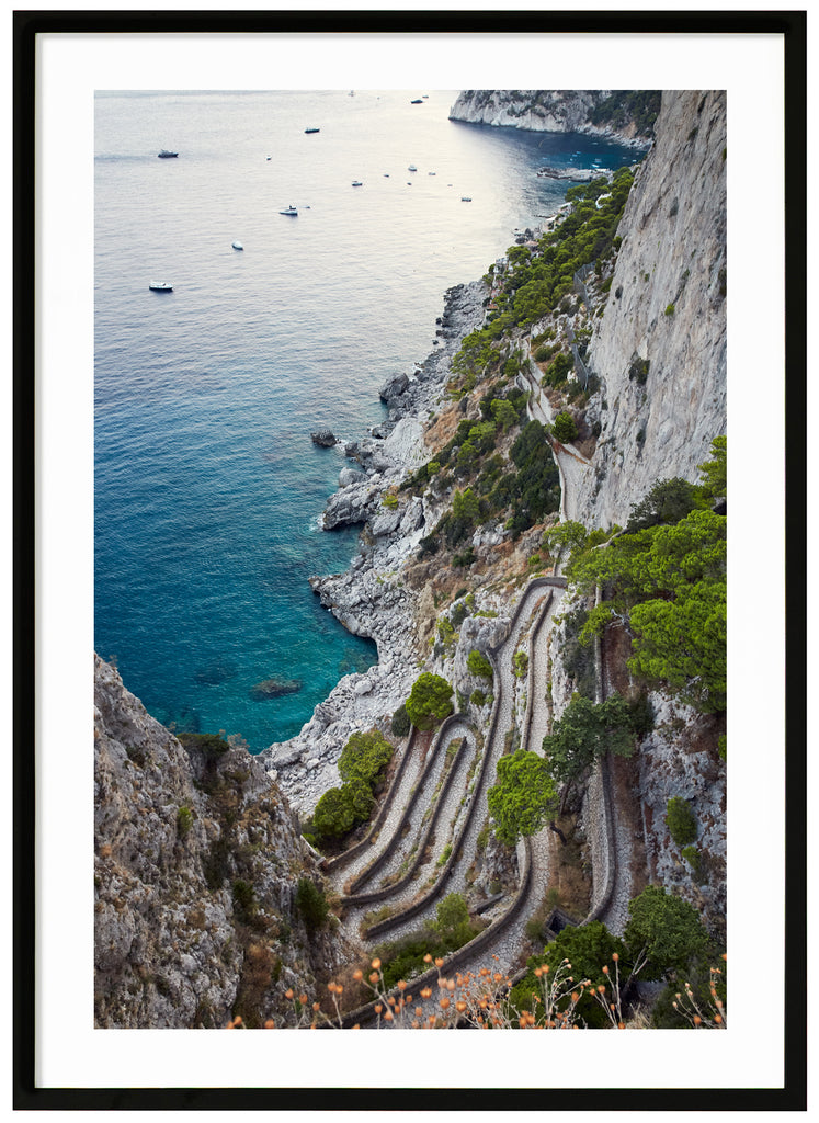 Color photography of a view of a stone promenade and boats on the Italian island of Capri. Black frame. 