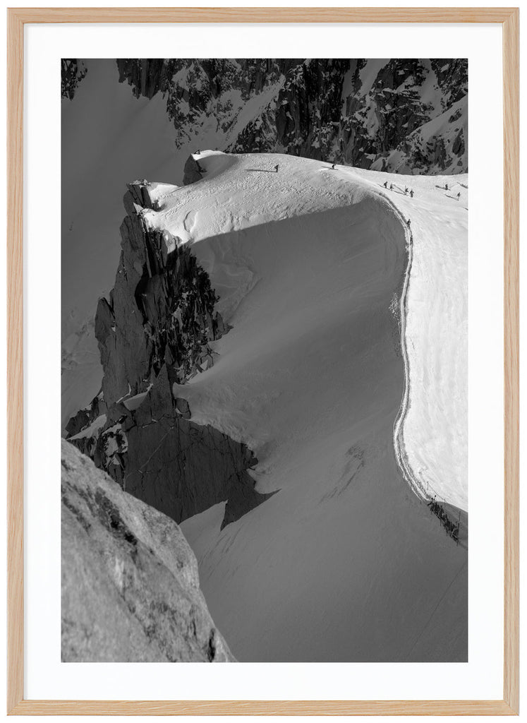 Black and white photograph of skiers hiking on snow-capped mountain ridge in the French Alps. Oak frame. 